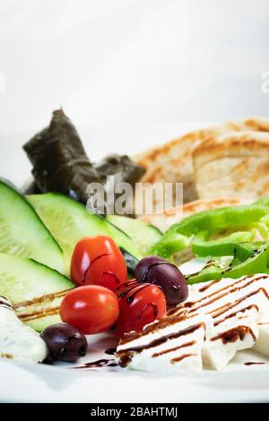 Semplice piatto di meze greco; con verdure, pita, foglie di uva, feta e smalto balsamico Foto Stock