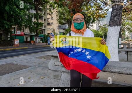 Una donna, nonostante la quarantena dichiarata, protesta contro il governo di Nicolas Maduro. Venezuela decreta la quarantena in 7 entità dopo l'aumento di p Foto Stock