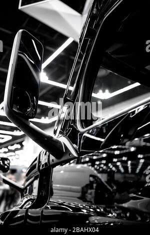 Parte laterale del trasporto merci commerciale elegante trattore semi-autocarro nero grande RIG con specchietto retrovisore e luce riflettente della portiera anteriore su t. Foto Stock