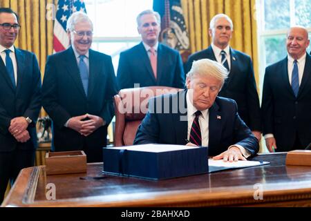 Washington, Stati Uniti d'America. 27 marzo 2020. Il presidente Donald J. Trump firma il "Coronavirus Aid, Relief, and Economic Security (CARES) Act", un progetto di legge di assistenza d’emergenza da 2.2 trilioni di dollari in risposta alla pandemia di coronavirus venerdì 27 marzo 2020, presso l’Ufficio ovale della Casa Bianca. Persone: Presidente Donald J. Trump Credit: Storms Media Group/Alamy Live News Foto Stock