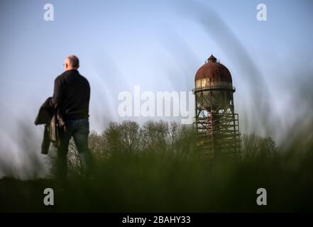 Dortmund, Germania. 27 marzo 2020. Un uomo cammina alla luce del sole della sera al cosiddetto uovo di Lanstroper. Quest'anno, la Fondazione tedesca per la protezione dei Monumenti intende sostenere il restauro di circa 45 monumenti nella Renania Settentrionale-Vestfalia. Uno dei principali progetti è il cosiddetto Lanstroper Egg, un serbatoio di acqua ad alto livello risalente al 1905. Credit: Bernd Thissen/dpa/Alamy Live News Foto Stock