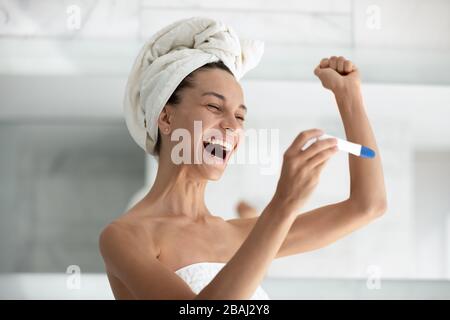 Donna eccitato applicare il test di gravidanza vedere due strisce si sente felice Foto Stock