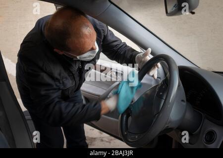 L'uomo turco di mezza età disinfetta la sua auto come precauzione per il virus pandemico della corona Foto Stock