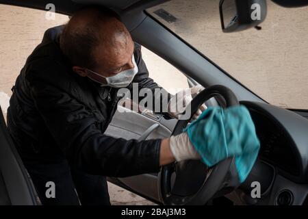 L'uomo turco di mezza età disinfetta la sua auto come precauzione per il virus pandemico della corona Foto Stock