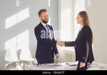 Colloquio di lavoro di successo. La conclusione del contratto. Uomo d'affari e donna d'affari si stringono al tavolo dopo la riunione. Foto Stock