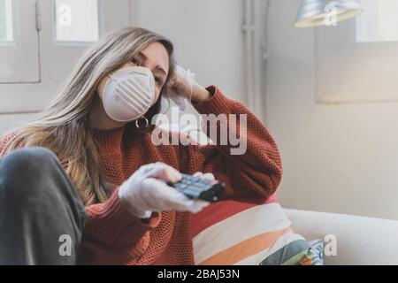 Coronavirus. Donna con maschera facciale e guanti in gomma che puliscono il suo spazio di lavoro con un disinfettante a casa durante l'epidemia di coronavirus. Prevenzione Foto Stock