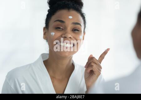Donna africana ha applicato crema sul viso la cura della bellezza della pelle Foto Stock