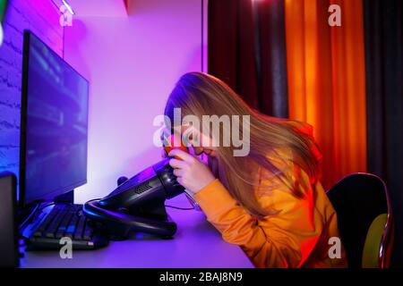 ragazza gamer che gioca a correre su un computer. Utilizza un volante. Gioco emotivo Foto Stock