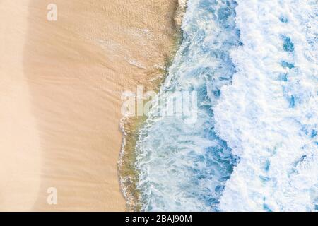 Vista dall'alto, splendida vista aerea delle onde che si infrangono su una splendida spiaggia durante una giornata di sole. Spiaggia di Nyang Nyang, Bali sud, Indonersia Foto Stock