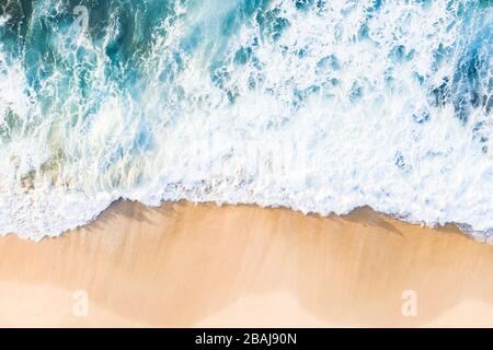 Vista dall'alto, splendida vista aerea delle onde che si infrangono su una splendida spiaggia durante una giornata di sole. Spiaggia di Nyang Nyang, Bali sud, Indonersia Foto Stock