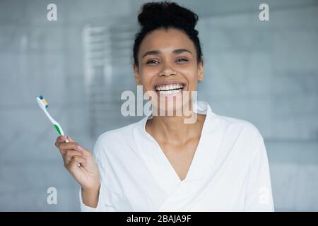 Ritratto della testa donna africana che tiene lo spazzolino sorridente guardando la macchina fotografica Foto Stock