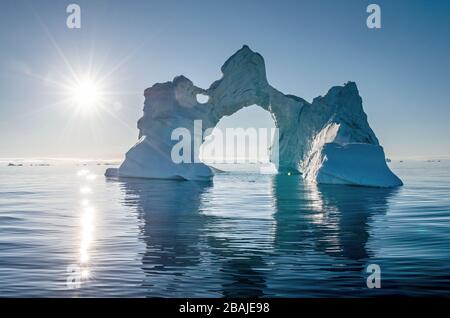 Iceberg durante l'alba con retroilluminazione dai raggi solari. Disko Bay, Groenlandia occidentale. Foto Stock