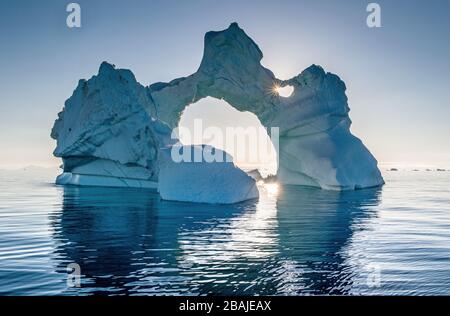 Iceberg durante l'alba con retroilluminazione dai raggi solari. Disko Bay, Groenlandia occidentale. Foto Stock