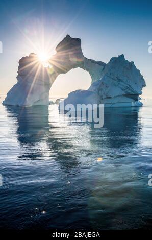 Iceberg durante l'alba con retroilluminazione dai raggi solari. Disko Bay, Groenlandia occidentale. Foto Stock