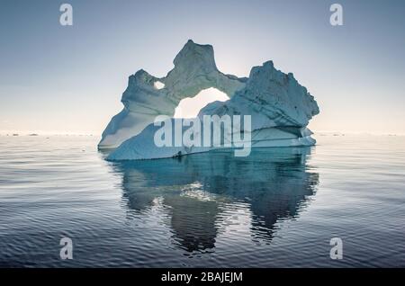 Iceberg durante l'alba con retroilluminazione dai raggi solari. Disko Bay, Groenlandia occidentale. Foto Stock