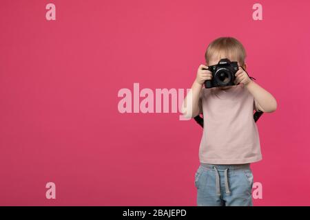 SAINT-PETERSBURG, RUSSIA - 22 MARZO 2020: Un bambino ragazzo si alza e tiene nelle sue mani una fotocamera Canon 70d con un obiettivo con un EF 50mm 1.4 montare e prendere Foto Stock