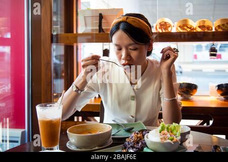 Donne che mangiano pollo al barbecue tailandese e manzo serviti sul piatto con zuppa tom yum in un pasto tailandese Foto Stock