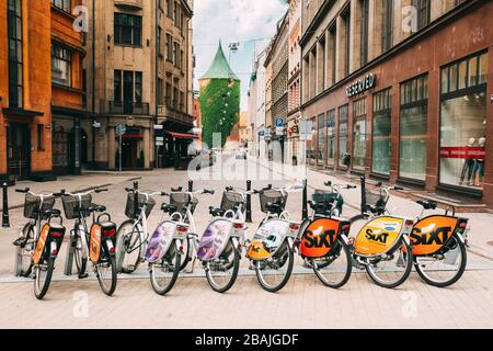 Riga, Lettonia - 2 Luglio 2, 2016: fila di colorati biciclette a noleggio a livello comunale Parcheggio bici In Kalku Street, Showplace popolare della città vecchia in giorno d'estate. Foto Stock