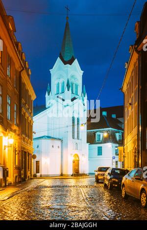 Riga, Lettonia - 3 luglio 2016: Torre bianca con la guglia piramidale di nostra Signora dei dolori o Vergine della Chiesa angoscia, Chiesa cattolica antica su Pils Ste Foto Stock