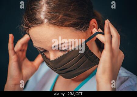 Primo piano ritratto donna, giovane donna che indossa a casa maschera igienica viso per prevenire infezioni, malattie o influenza e 2019-nCoV. Sfondo nero Foto Stock