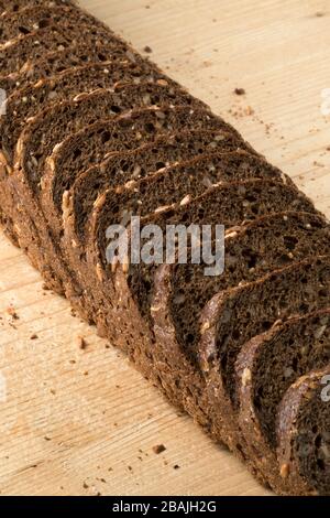 Pane fresco a fette di pane a grana multipla su tavola di legno Foto Stock
