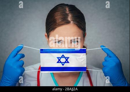 Coronavirus in Israele femmina Dottore Ritratto tenere proteggere viso maschera medica chirurgica con Israele Bandiera Nazionale. Malattia, virus Covid-19 in Israele, con Foto Stock