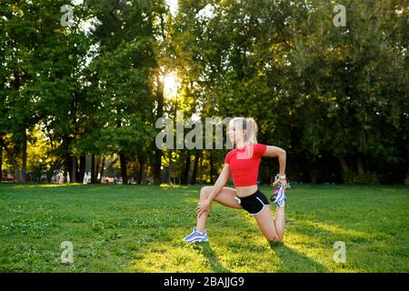 Una giovane ragazza sulla natura sta facendo corsi di yoga di allungamento della gamba nel Parco. Foto Stock