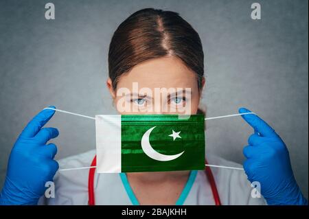 Coronavirus in Pakistan femmina medico ritratto tenere proteggere viso maschera chirurgica medica con Pakistan Bandiera Nazionale. Malattia, virus Covid-19 a Pakista Foto Stock