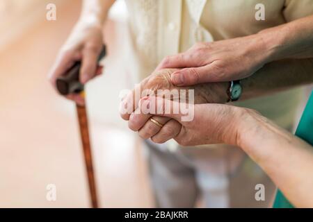 Infermiere consolante il suo paziente anziano tenendole le mani Foto Stock