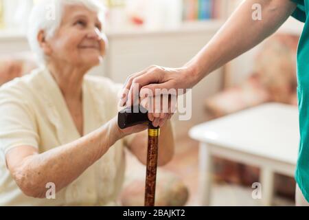 Infermiere consolante il suo paziente anziano tenendole le mani Foto Stock