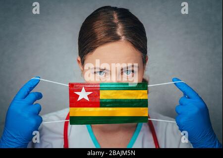 Coronavirus in Togo Donna Dottore Ritratto Hold proteggere viso maschera medica chirurgica con Togo Bandiera Nazionale. Malattia, virus Covid-19 in Togo, concetto p Foto Stock