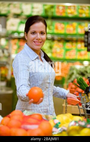 Junge Frau kauft im Supermarkt Lebensmittel und Obst ein, MR: Sì Foto Stock