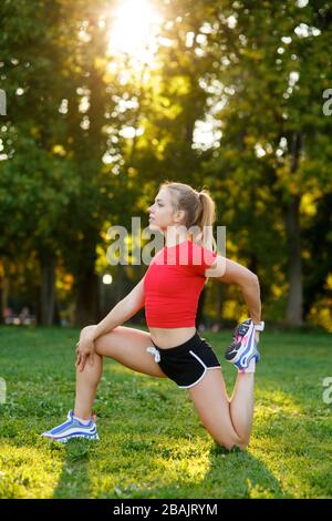 Una giovane ragazza sulla natura sta facendo corsi di yoga di allungamento della gamba nel Parco. Foto Stock