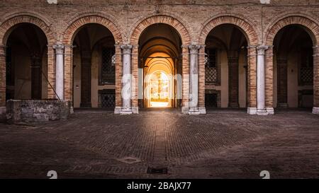 Archi di Palazzo Venieri con luce del sole d'oro che splende attraverso la porta d'ingresso, Recanati, Italia Foto Stock