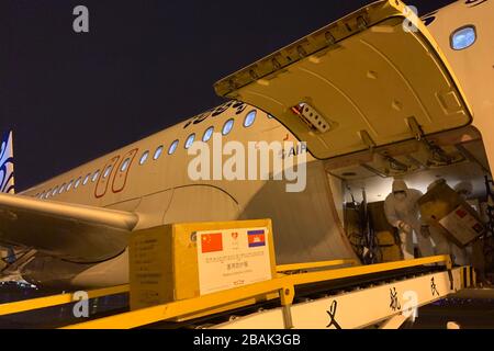 Jinhua, provincia cinese di Zhejiang. 27 marzo 2020. Il personale carica i materiali di prevenzione epidemica per la Cambogia su un aereo all'aeroporto internazionale di Yiwu in Yiwu, provincia di Zhejiang della Cina orientale, 27 marzo 2020. Un lotto di materiali di prevenzione epidemica è stato caricato su un aereo diretto per la Cambogia il venerdì dopo essere passato attraverso il 'passaggio verde' istituito presso la stazione di ispezione di frontiera di entrata-uscita della difesa nell'aeroporto internazionale di Yiwu. Credit: Li Jinliang/Xinhua/Alamy Live News Foto Stock