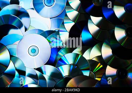 Gruppo di supporti di memorizzazione per dischi ottici CD DVD compatti con polvere e graffi. Spettro arcobaleno di colori iridescenti. Luce di messa a fuoco Foto Stock