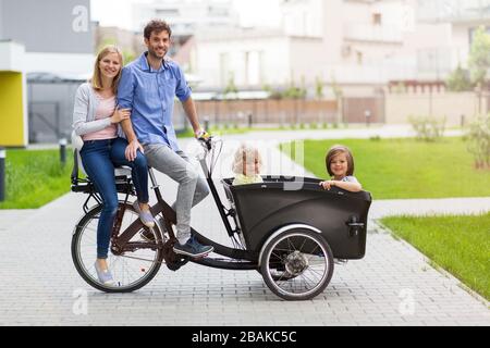 Giovane famiglia che ha un giro con la bici di carico Foto Stock