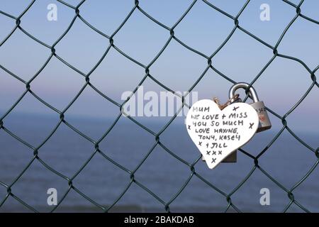 Un memoriale ad un parente defunto legato ad una recinzione in cima ad una scogliera a Whitby Harbour. Distanza sociale, strade vuote e negozi chiusi nella località turistica del North Yorkshire di Whitby durante ‘Lockdown’, nella Pandemia di Coronavirus. Foto Stock