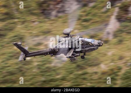 United Kingdom Army Air Corps AH-64 Apache attacco elicottero di volo basso livello in una valle gallese Foto Stock