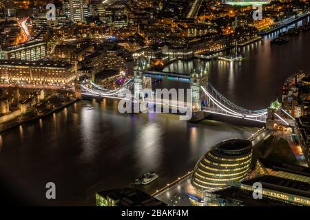 Tower Bridge sopra il Tamigi di notte con edifici illuminati, la torre di Londra e conduce verso Canary Wharf Foto Stock