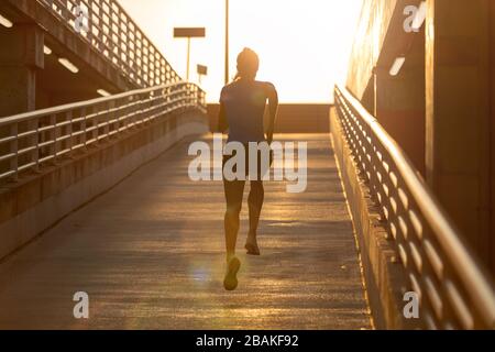 Giovane donna che fa esercizio di fitness a livello di parcheggio in città al tramonto Foto Stock