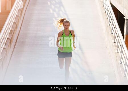 Giovane donna che fa esercizio di fitness a livello di parcheggio in città al tramonto Foto Stock