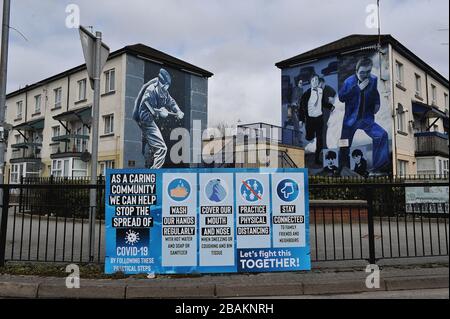 Firma con consigli su COVID-19 evitare accanto a murales nel Bogside, Derry, Irlanda del Nord. ©George Sweeney / Alamy Stock Photo Foto Stock