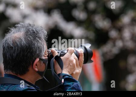 Tokyo, Giappone. 28 Marzo 2020. Un uomo prende le foto dietro una corda per tenere il pubblico lontano dagli alberi dei ciliegi nel Parco di Ueno. Il governatore di Tokyo Yuriko Koike ha chiesto ai residenti di astenersi da tutte le uscite non essenziali e non urgenti questo fine settimana, tra cui la visione dei fiori di ciliegi, in mezzo a un aumento dei casi di infezione da coronavirus a Tokyo. Credit: Rodrigo Reyes Marin/ZUMA Wire/Alamy Live News Foto Stock