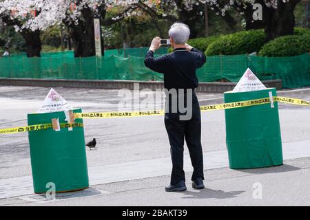 Tokyo, Giappone. 28 Marzo 2020. Un uomo prende le foto dietro una corda per tenere il pubblico lontano dagli alberi dei ciliegi nel Parco di Ueno. Il governatore di Tokyo Yuriko Koike ha chiesto ai residenti di astenersi da tutte le uscite non essenziali e non urgenti questo fine settimana, tra cui la visione dei fiori di ciliegi, in mezzo a un aumento dei casi di infezione da coronavirus a Tokyo. Credit: Rodrigo Reyes Marin/ZUMA Wire/Alamy Live News Foto Stock