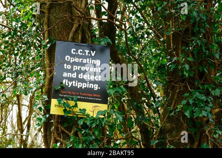 CCTV che opera per prevenire e rilevare il segnale Flytipping sul tronco dell'albero in un bosco in Weald di Kent vicino a Tunbridge Wells, Inghilterra Foto Stock