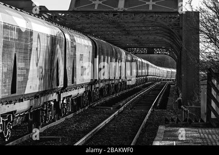 Lungo treno di carri ferroviari Drax Biomass che attraversano il ponte di King George V ad Althorpe, Lincolnshire Foto Stock