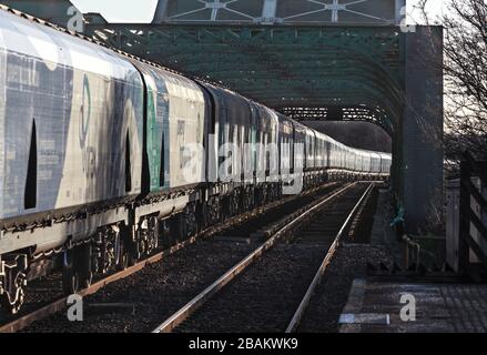 Lungo treno di carri ferroviari Drax Biomass che attraversano il ponte di King George V ad Althorpe, Lincolnshire Foto Stock