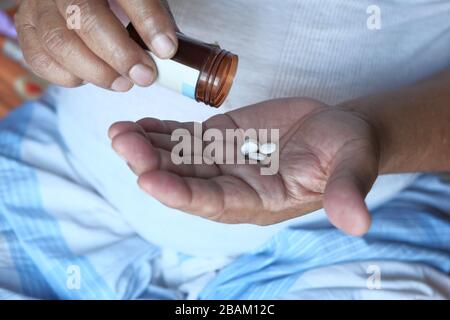Uomo anziano mano prendendo pillole dal contenitore , primo piano Foto Stock