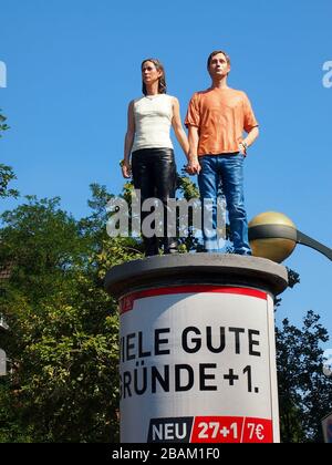 "Sviene sulle colonne": Opera di Christoph Pöggeler, raffigurante una scultura realistica di una coppia che si erge su un pilastro pubblicitario a Düsseldorf. Foto Stock